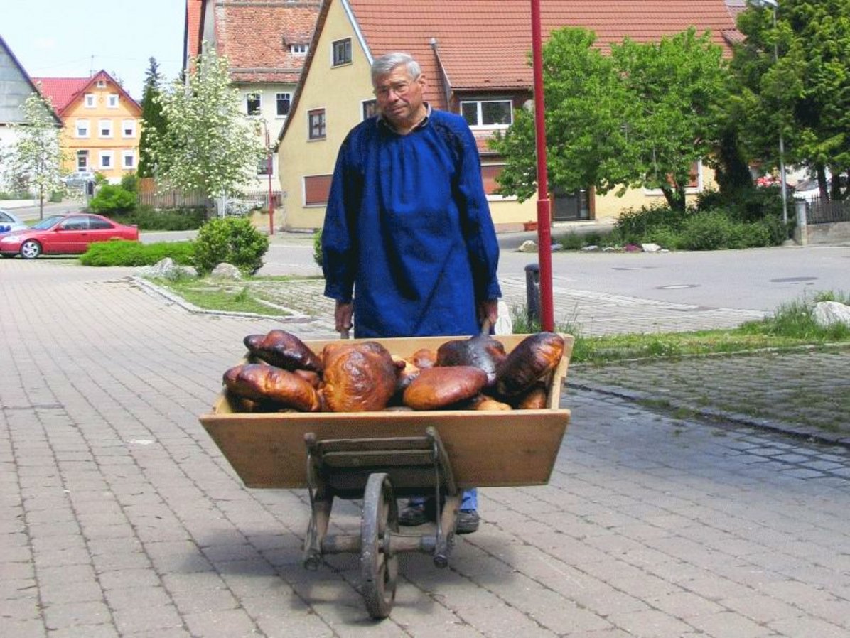 Person in Tracht beim Ausfahren von gebackenen Broten