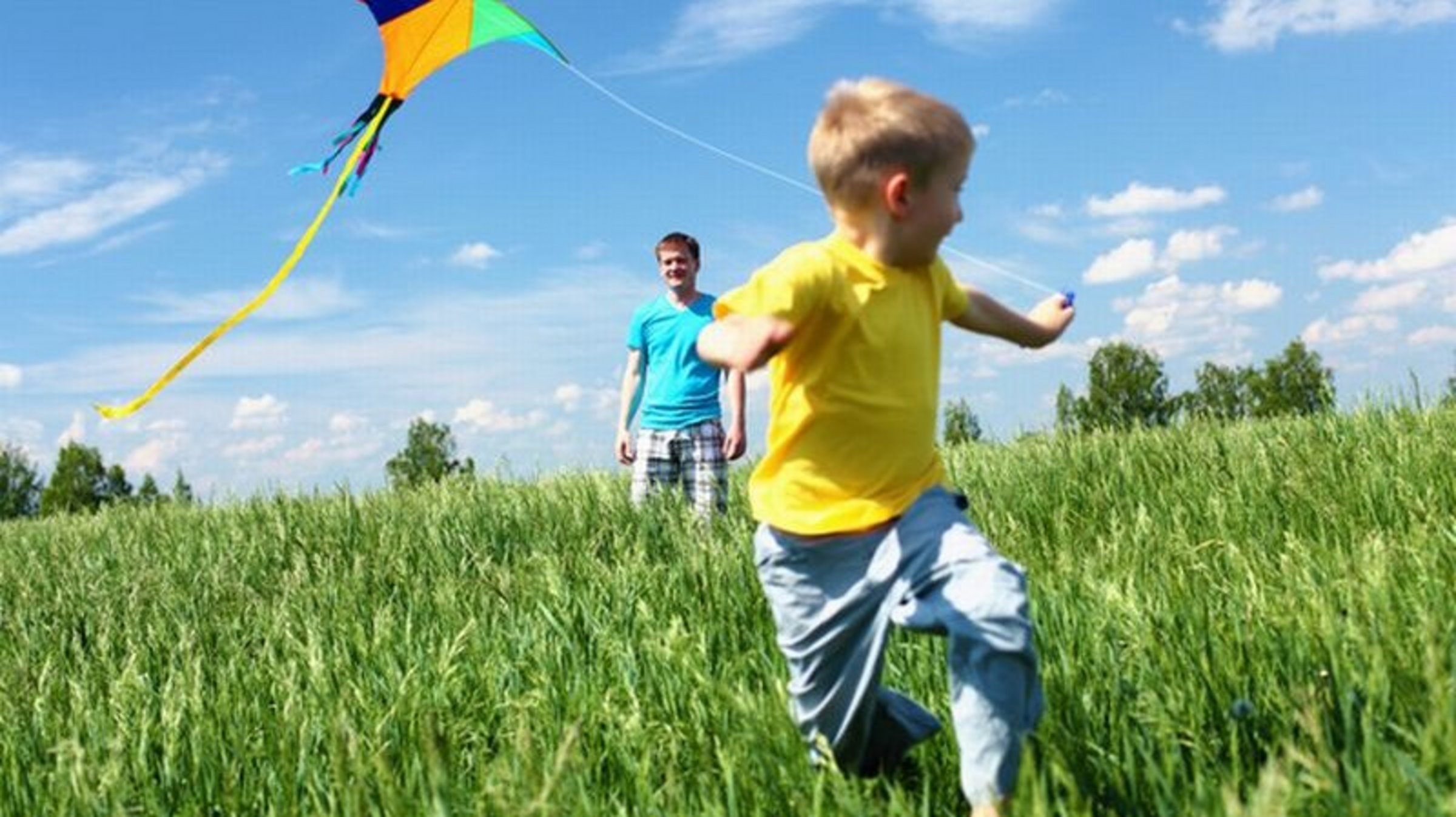 Kind mit Drachen auf einer Wiese spielend
